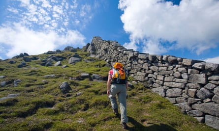 Walker neben der Mourne Wall beim Aufstieg von Slieve Bearnagh, Mourne Mountains, County Down, Nordirland, Vereinigtes Königreich.